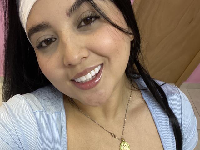 ShinyMurpy heeft een bruine huid, zwart haar, een witte hoofdband en een blauw gestreept topje. Ze glimlacht met glanzende witte tanden en draagt een gouden ketting met een klein hangertje..