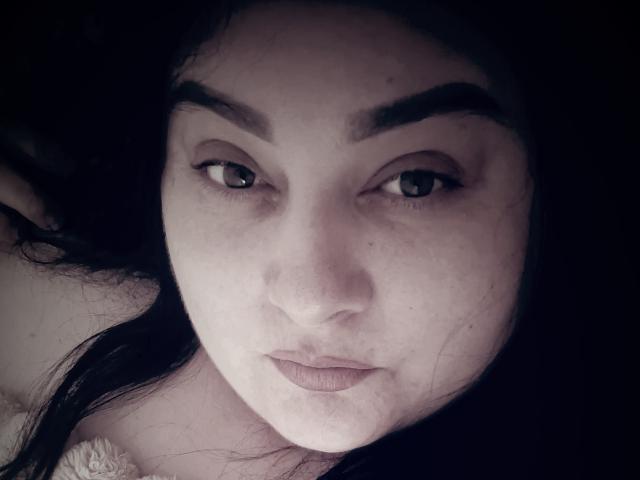 EleanorViski's face, showing dark eyebrows, light skin, brown eyes, and slightly parted lips. She has long black hair, and a fluffy collar is partially visible.