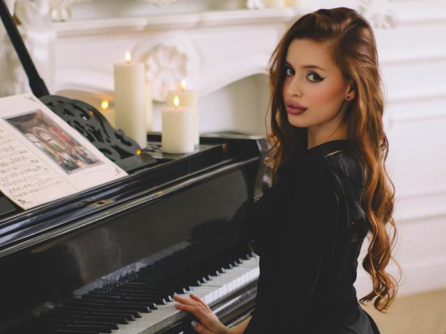 CherylFoxy with long, wavy brown hair, black dress, and red lipstick, playing a black piano, looking back with a sexy, sultry expression, candles lit in the background.