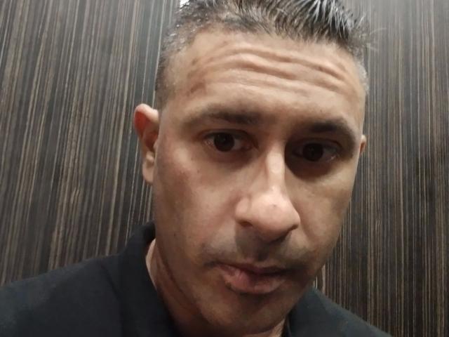 Uma selfie de leaveitinsideme-hot com cabelo curto e grisalho, com pontas, lábios levemente entreabertos e um pequeno corte no canto inferior direito do queixo. Ele está vestindo uma camisa preta..