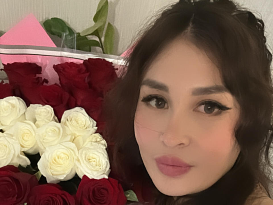 QeunSil ha i capelli castano chiaro, mossi, occhi scuri con un trucco per gli occhi molto marcato, rossetto rosa e un naso piccolo. Tiene in mano un bouquet di rose rosse e bianche..