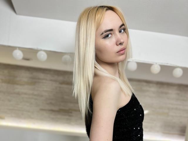 IriskaMimi with blonde hair, black sequin dress, nose ring, and heavy eyeliner, looking back over shoulder, soft light, slightly upturned nose, pale skin, subtle makeup, slim build.