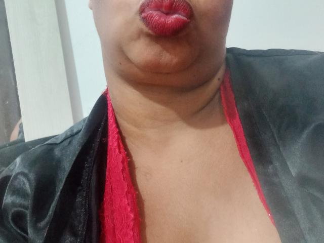 MiaMichelleHot's pouty red lips, black satin jacket, and red lace bra are prominently displayed, with her tan skin and double chin visible. Boobs partially covered by lace.