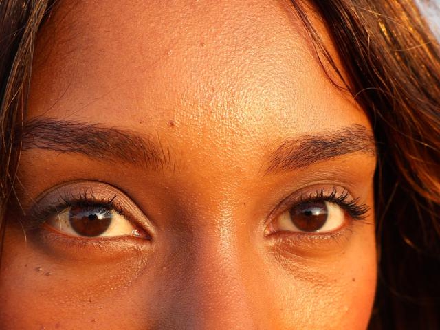 EmmaLatin's face, focusing on her brown eyes, slightly parted lips, and brown eyebrows with a hint of her brown, wavy hair on the sides. Her skin is warm-toned.