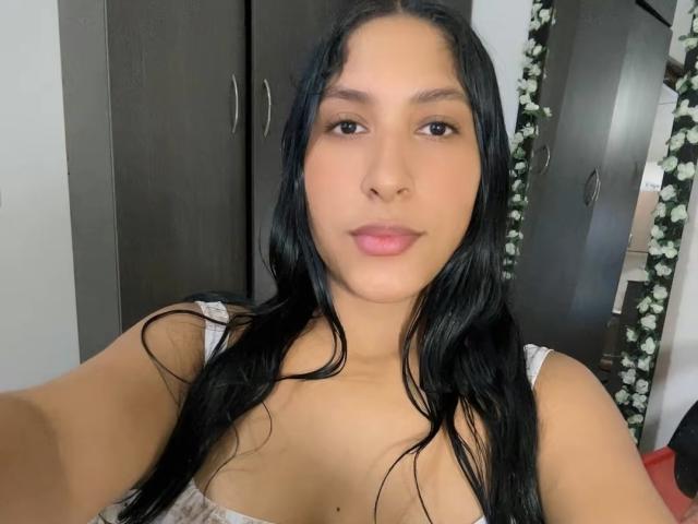 MadisonReyes with long black hair, light brown skin, and pink lips, wearing a striped tank top, showing small tits and a slightly visible cleavage in a selfie.