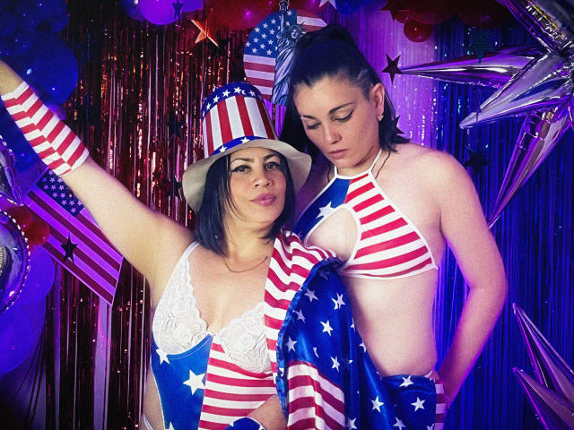 SaharaMK with tits in white lace bra, red and white striped top hat, and arm, standing next to SaharaMK with small ass, blue and white striped bikini, and flag.