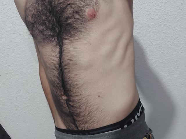 LapijArgie69's hairy chest with a visible nipple, slim ribs, and a small belly button. They're wearing gray pants with a black waistband.