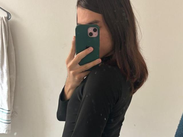 TamaraGarcia taking a mirror selfie, her face partially obscured by a green phone, wearing a black long-sleeve shirt, with medium brown hair.