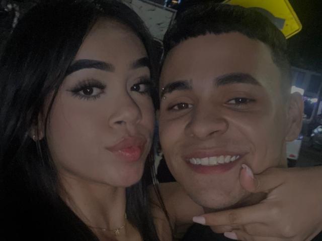 Isabella hat dunkles Haar, dicke Augenbrauen und zieht die Lippen zusammen. Matteo hat kurze Haare, ein Nasenpiercing und lächelt, wobei er mit seinem Finger ihre Wange berührt..