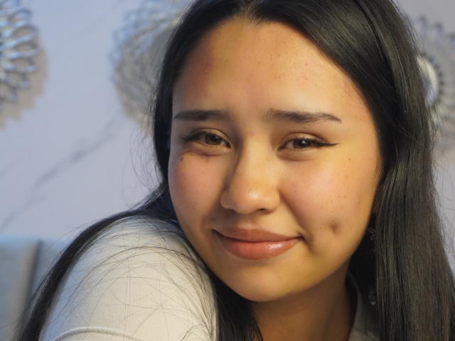 Karollteyes has a cute face with long black hair, light brown skin, and subtle eyeliner. She's smiling softly with a slight red mark on her forehead.