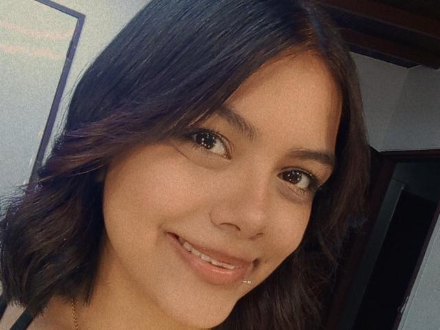 EmilyRoberts has medium brown skin, dark brown shoulder-length hair, and is smiling with a nose ring and lip piercing, showing her cute face and brown eyes.