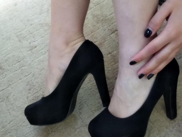 Le gambe pallide di Nurri, indossava scarpe nere con tacchi alti, e la sua mano con le unghie nere toccava la caviglia. Si vedeva la trama del tappeto..