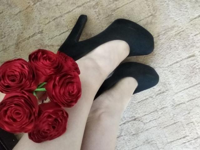 Las piernas pálidas de Nurri estaban cruzadas en el tobillo, vestía unos tacones negros altos, y un ramo de rosas rojas descansaba sobre sus dedos de los pies..