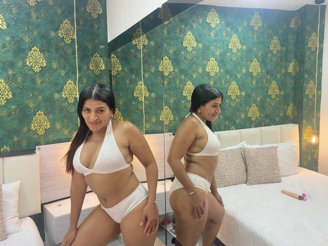 OrionSmith in white bikini, showing her ass and tits, standing in front of a mirror, smiling, with a reflection of her ass and tits. Bedroom, green wallpaper.
