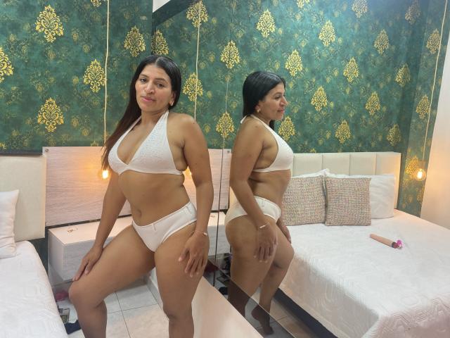 OrionSmith with tan skin and dark hair, wearing a white lace bikini, has a curvy, full-figured body with large ass and small tits, standing in front of a mirror.