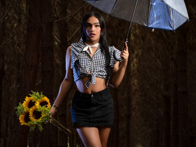 IrinaFerrero with black-and-white checkered shirt tied above tits, black skirt, holding sunflowers and umbrella, dark forest background, long black hair, white choker, sexy, confident pose.