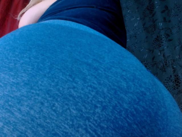 HoneySweett's big, round ass in tight, blue, textured fabric. Her black top is visible above. She has light skin and blonde hair. The image is a photo.