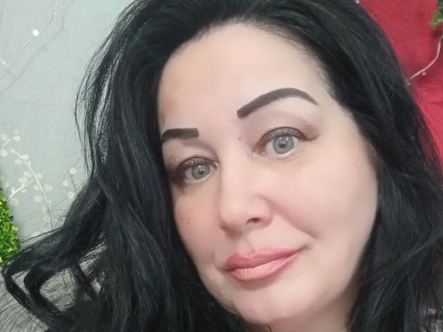 LexyRose has black hair, thick eyebrows, green eyes, and pink lips, with a slight smile. Her skin is pale, and she looks cute. She's a sexy woman.