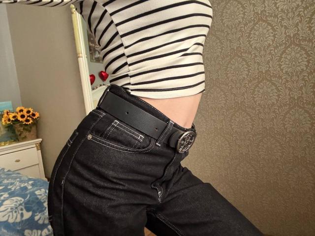 Siyana's striped shirt, black belt with silver buckle, and dark jeans show her slim waist and flat stomach. Her black belt sits just above her ass.