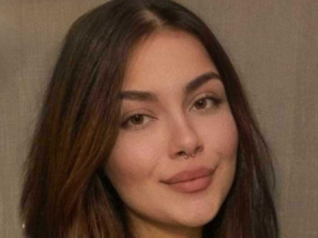 SexyRedLucy with brown hair, brown eyes, and a nose ring, smiling softly at the camera, showing a slight pout and natural makeup, looking cute and attractive.
