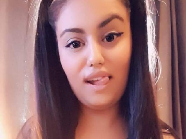 RubyFiera has medium brown skin, black eyeliner, and pouty lips with a slight smirk. She's looking at the camera with straight, black hair in pigtails.