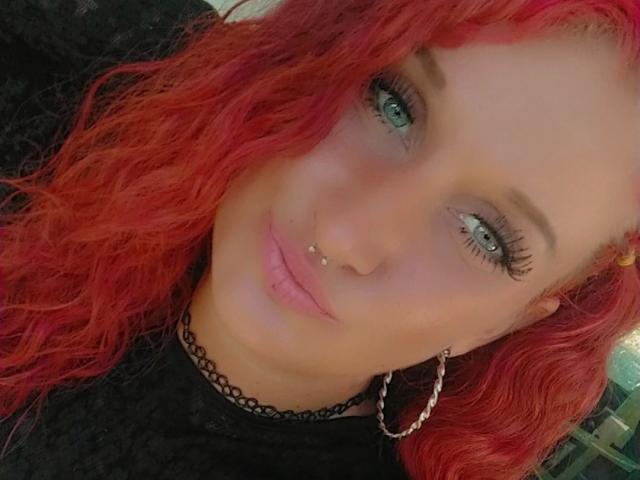Licaink-hot ha i capelli rossi e ricci, gli occhi verdi, l'eyeliner nero, le ciglia lunghe, un anello al naso, un piercing al labbro e indossa una collana nera con una catena d'argento come orecchino..