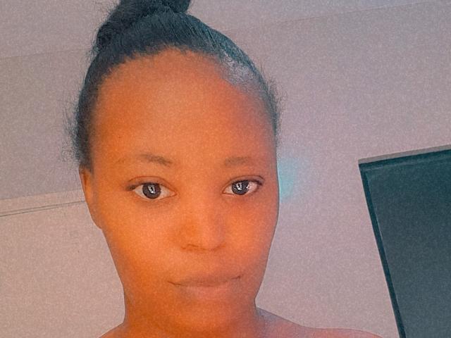 SpicyPie has brown skin, small nose, and a subtle smile. She has dark eyes, a top bun hairstyle, and is looking at the camera with a calm expression.