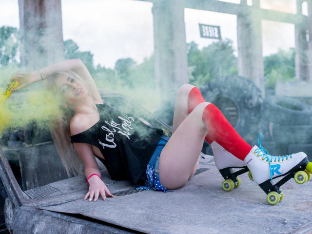 LindaBryns with red knee socks, blue shorts, black shirt, and roller skates, smoking yellow smoke, leaning against a car, showing her ass, and wearing white roller skates.