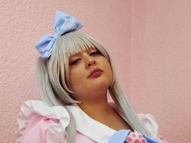 SpacyBabe69 with light gray hair, blue bow, pink and white puffy sleeves, white collar, and pink eyeshadow, looking slightly up with a confident expression.