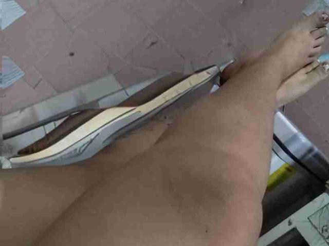 TugorditaSexy's bare legs and feet are in the frame, with a pair of sneakers partially covering their pussy. The focus is on their lower body from a top-down angle.