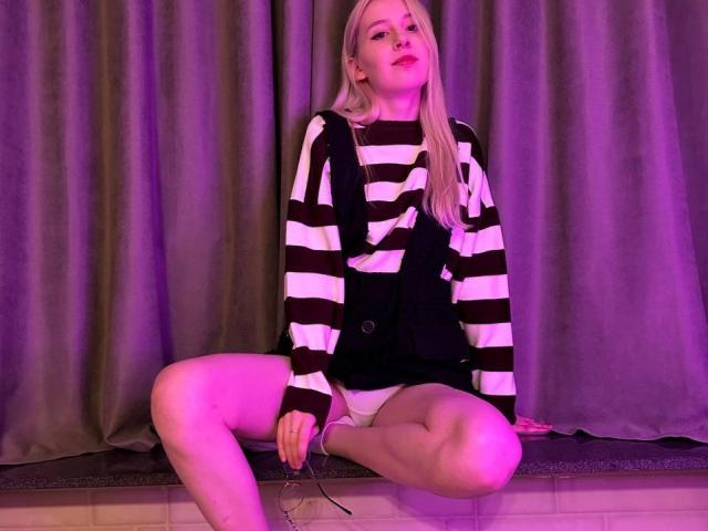 Vip-Paare mit blonden Haaren, einem schwarz-weißen Streifenhemd, schwarzen Shorts und weißen Unterhosen, die mit gespreizten Beinen sitzen, in violettem Licht, mit Blick nach oben, Hände auf dem Boden..
