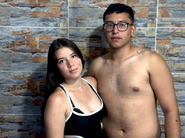 BellaThorSexUnlimit with black hair, small tits in black tank top, stands next to shirtless BellaThorSexUnlimit with glasses, chest hair, and small tattoo on right shoulder.