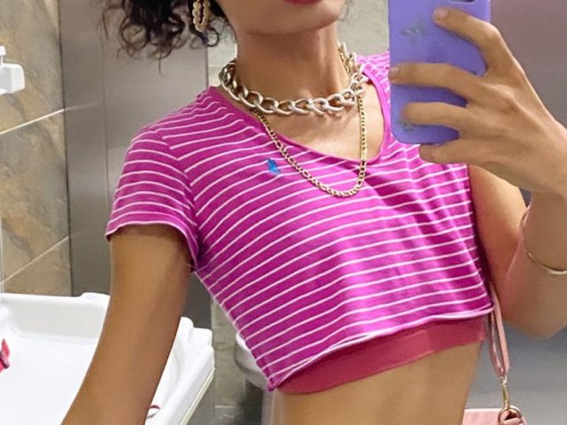 SweetSamyPrincipal's pink striped crop top, showing small tits, red bra, gold chain, purple phone, curly brown hair, and pink crossbody bag, taking a mirror selfie.
