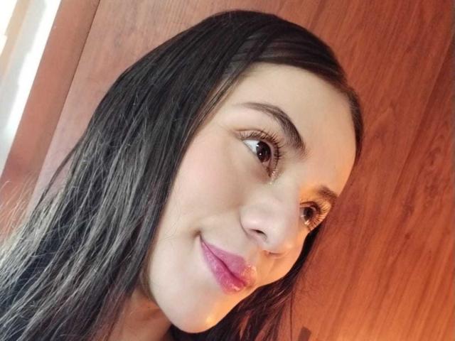 OshumBae has dark brown hair, brown eyes, and pink lips with a slight smile. Her face is turned slightly to the right, showing a soft, relaxed expression.