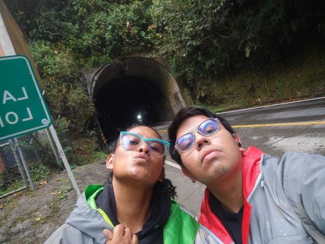 JuliaxRosee has puffy ass lips, wearing green and gray jackets, with blue glasses, next to JuliaxRosee with puffy ass lips, wearing red and gray jacket, in a selfie.