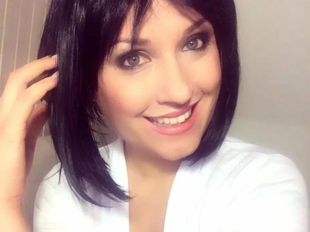 MissDoertie - morena, com cabelo curto preto, sorrindo com lábios rosados, camisa branca, segurando o cabelo, olhos castanhos, pele clara, maquiagem suave, fofa e atraente, sexy..