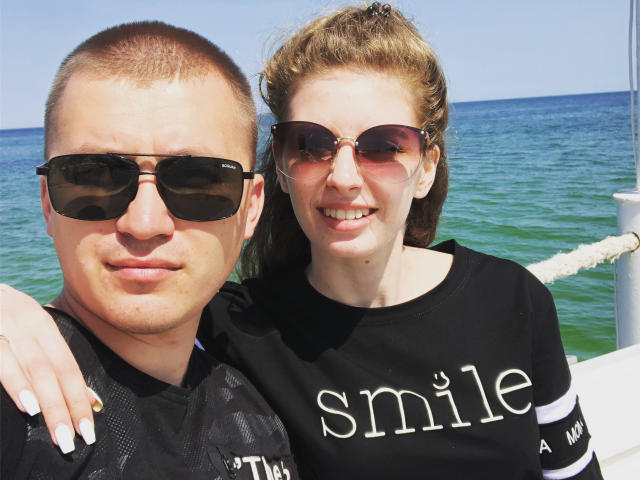 LoganEmma tiene el pelo corto y castaño y lleva gafas de sol oscuras, de pie junto a una mujer con el pelo rizado rubio y gafas de sol marrones. Ambas llevan camisetas negras. Se ve el océano al fondo..