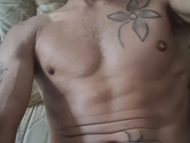 Martinleck54-hot's bare, muscular chest with small, hard nipples and a tattoo of a flower on his right pectoral. His skin is slightly tan with visible chest hair.