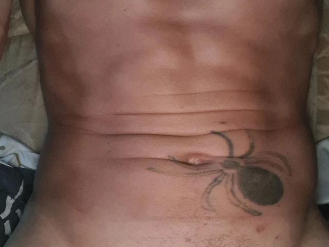 Martinleck54-hot's tan, bare, muscular belly with a black and brown spider tattoo just above their hairy, slightly curved, and visible, flaccid, circumcised, erect-looking, dark-skinned, soft-penised, navel.