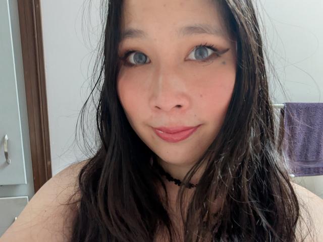 DiamondShadows has wet black hair, blue eyes, and pink lips with a slight smile. She's wearing a black necklace and has a cute, slightly flushed face.