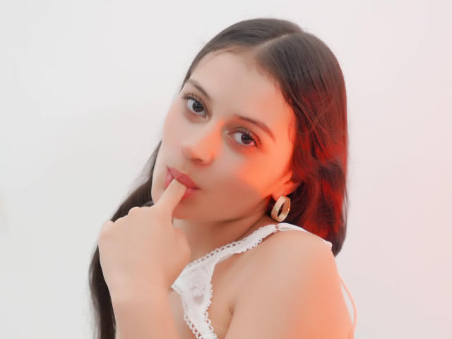 LizzaRose with long dark hair, pouty lips, finger in mouth, white lace top, small tits, light skin, brown eyes, red light, gold earrings, soft focus, cute, sexy.