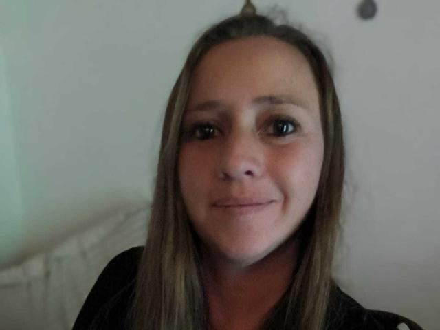 CelesteStorm with straight brown hair, fair skin, and a subtle smile, wearing a black shirt, has small, cute tits and slightly flushed cheeks. She's looking directly at the camera.