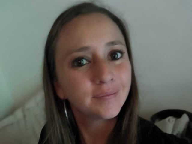 CelesteStorm has brown hair, green eyes, and a slight smile. She's wearing a black top with silver hoop earrings, and her nose is small and slightly upturned.