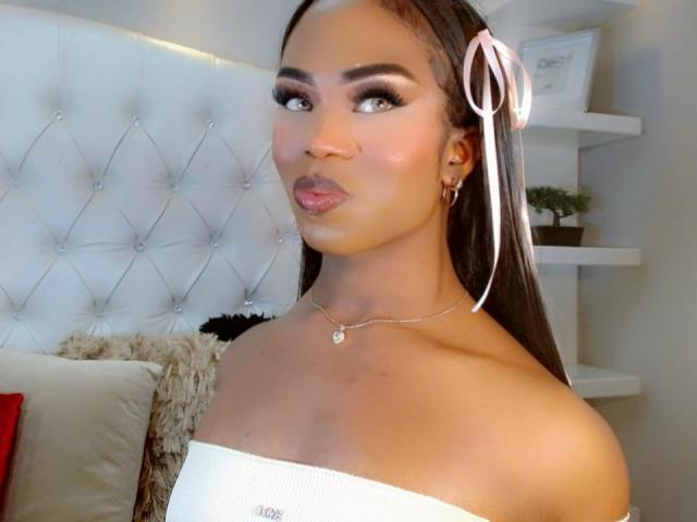 DarlingSweety with long brown hair, pink ribbons, white off-shoulder top, and shiny makeup, looking to the side with pouty lips, wearing a necklace with a small gem.