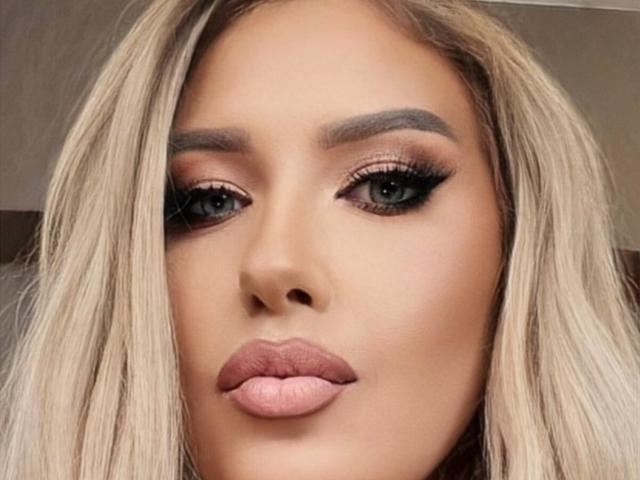 OndinaNoir's face, blonde hair, brown eyes, thick black eyeliner, long lashes, full pink lips, subtle eyebrow, smooth skin, centered in the image, looking slightly to the left.