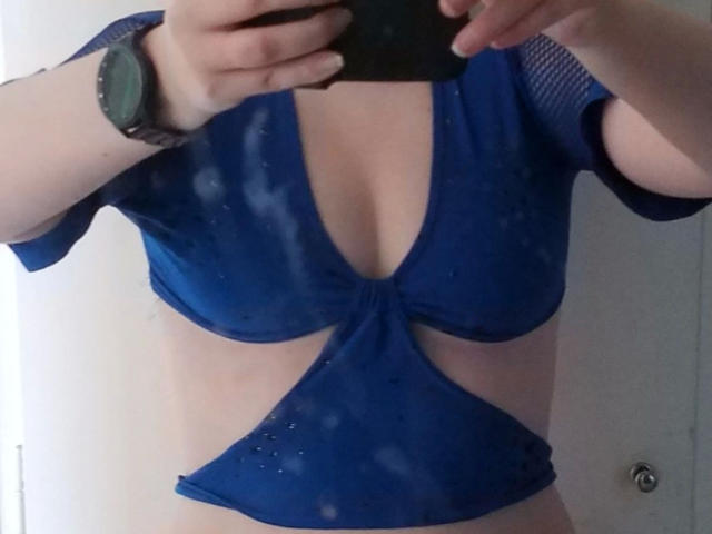 Spielzeuglena-hot in a blue mesh top with a deep V-cut, exposing her tits and showing a small patch of her ass. She's wearing a green watch.