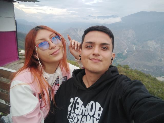 Loren has red hair, blue aviator glasses, and a pink jacket with white sleeves, next to Ethan69, who's wearing a black "Vomor" hoodie, making a peace sign.
