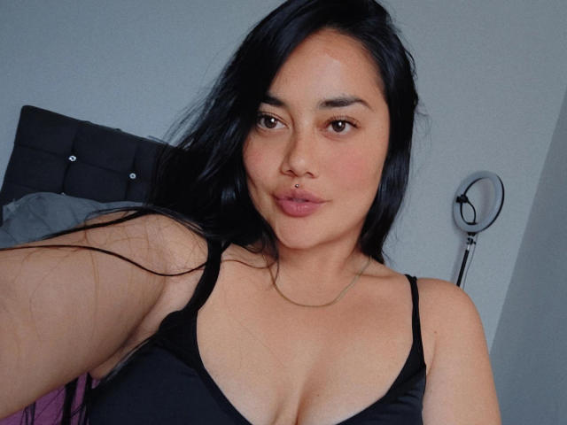 SamaraHotty69 with black hair, brown eyes, and a nose ring, wearing a black tank top, showing her cleavage and puffy lips, in a selfie. Her tits are visible.