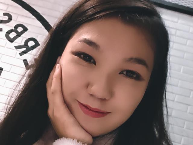PeachyPalette has a cute face, long dark hair, and is smiling with her hand on her cheek. She has light skin, black eyes, and red lipstick.