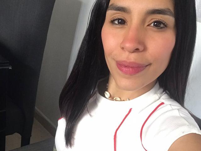 Madison Roberts ha i capelli neri e lisci, occhi marroni, labbra rosa e indossa una camicia bianca con righe rosse. Porta una collana di conchiglie ed è sorridente. Il seno non è visibile..